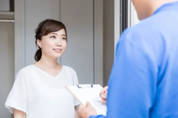 玄関で作業内容の説明を受ける女性